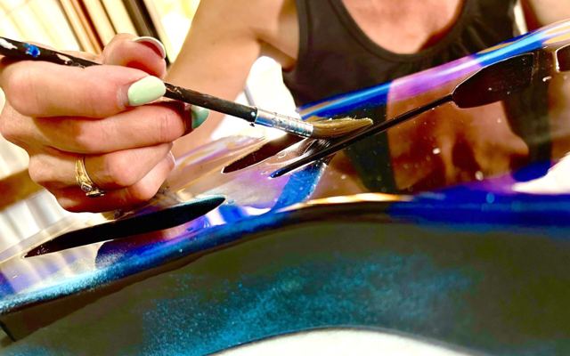 Pennello che stende il colore blu sul corpo della chitarra