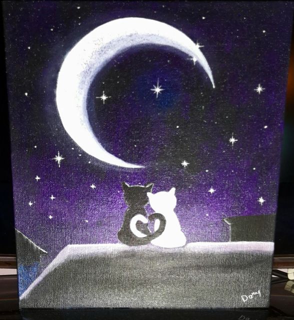 Due gatti abbracciati su un tetto sotto la luna