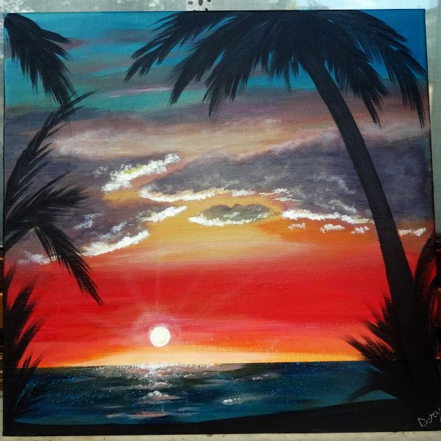 Tramonto rosso sul mare tra le palme